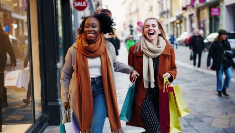 two happy friends shopping on a bustling city street