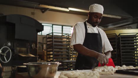Animation-of-happy-african-american-male-baker-cutting-sourdough-for-bread