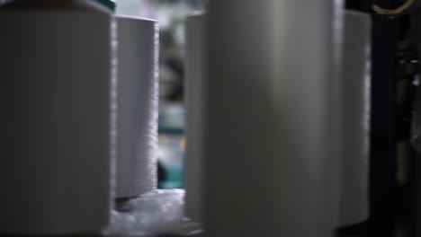 the process of manufacturing of socks on a loom - close-up shot of spools with white thread at rewinding machine video