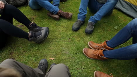 a group of people's feet and legs sitting on green grass outdoors