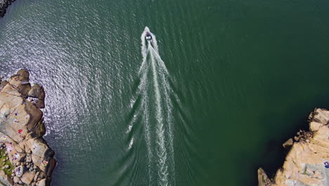 Powerboat-Cruising-And-Leaving-Wake-On-The-Calm-Blue-Sea-In-Saltholmen,-Gothenburg,-Sweden-With-Sunlight-Reflection-On-The-Water---aerial-drone