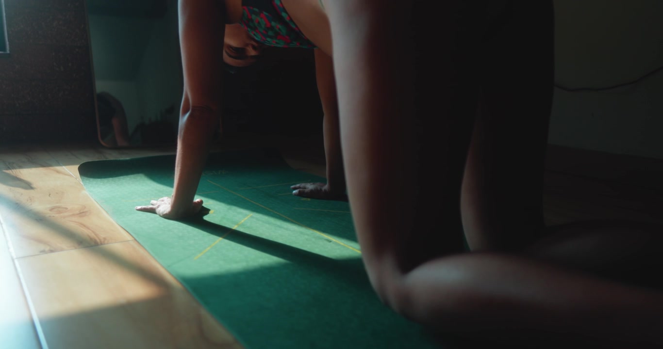Woman performing alternating knee lift movements on a yoga mat, focusing on core stability, balance, mobility, and controlled fitness training indoors.