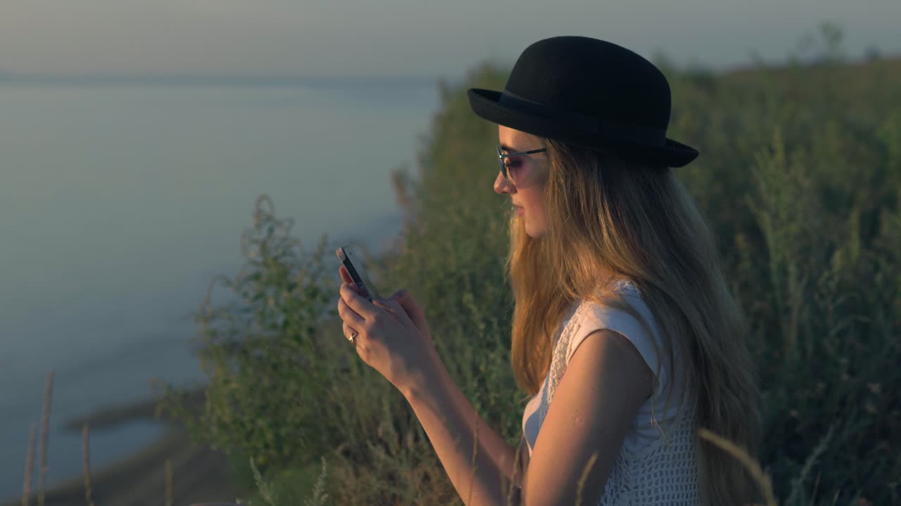 Woman using phone at sunset riverside