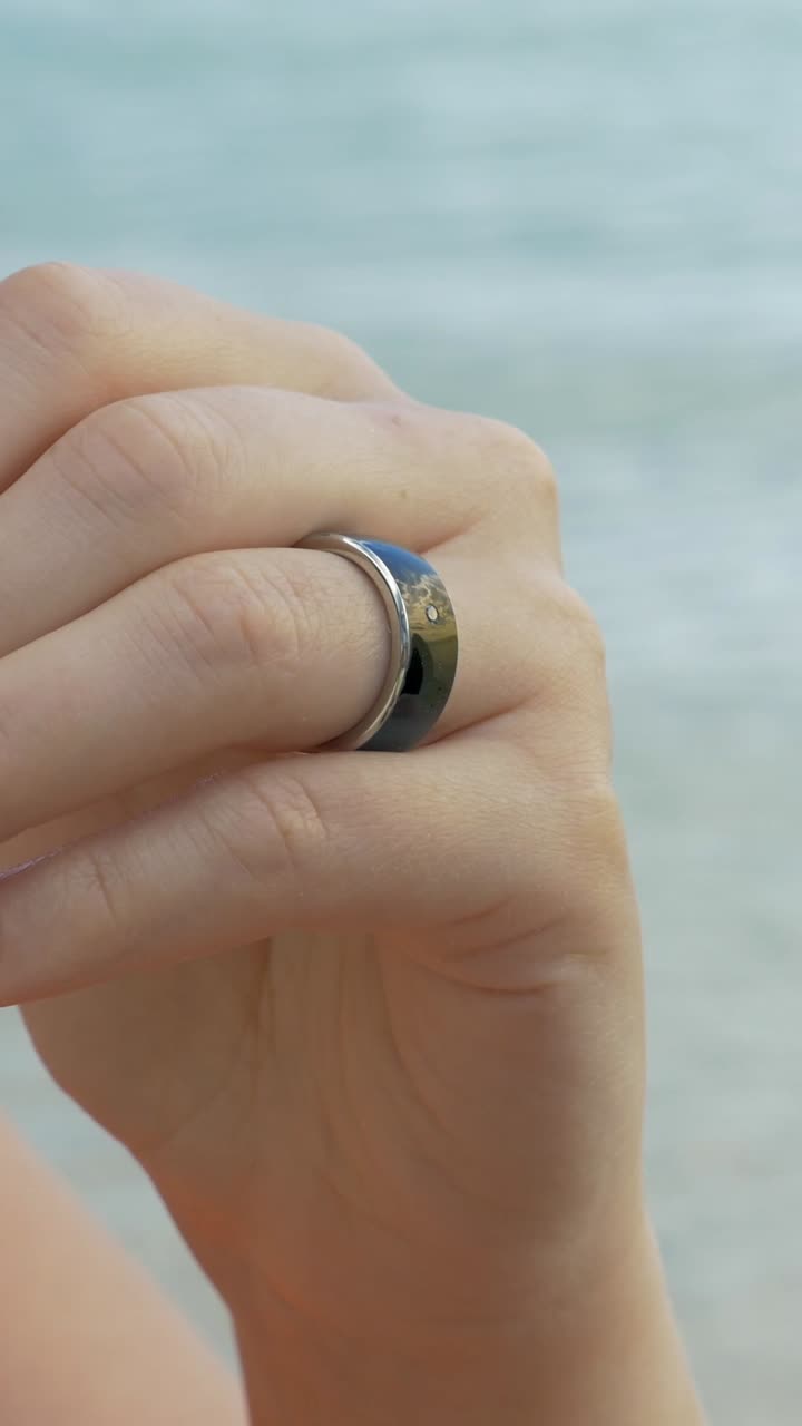 Primo piano di una mano che indossa un anello intelligente vicino all'acqua