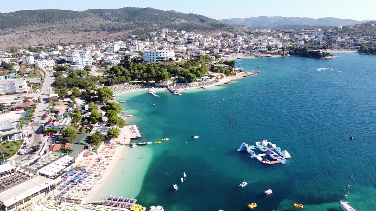 Ksamil, Arnavutluk - Oteller, Plaj Kulübü, Şezlonglar, Su Oyun Alanı ve Ada içeren Popüler Tatil Destinasyonunun Geriye Doğru Havadan Çekimi