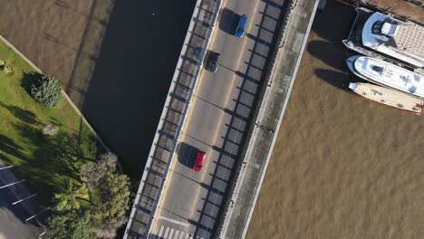 aerial birds eye shot of cars crossing small bridge during sunny day in tigre,argentina