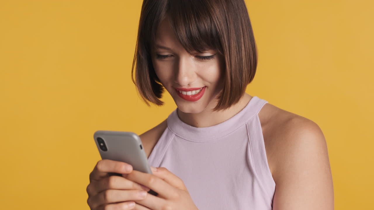 chica sensual mordiéndose el labio mientras usa su teléfono inteligente