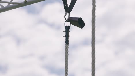 Rope-climber-rings-cowbell-at-top-of-rope-during-military-obstacle-course-training-race-close-up-slow-motion-4k