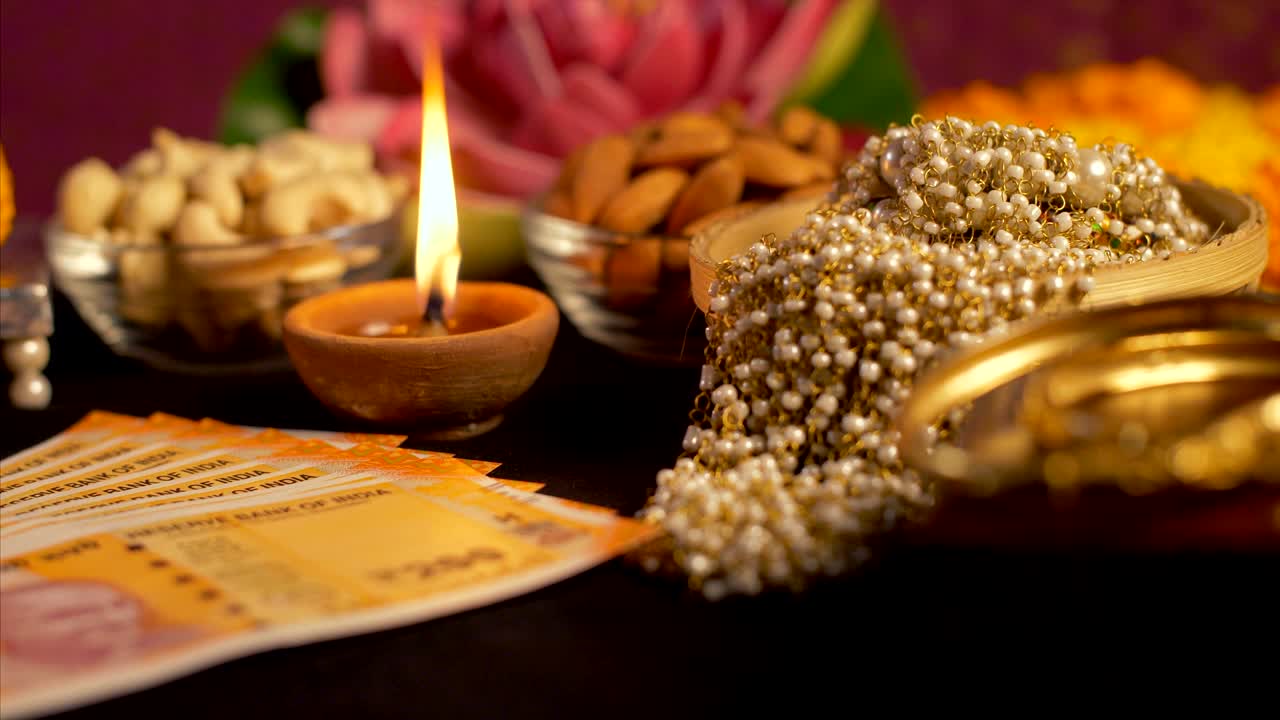 Pan shot of Indian currency / money, jewellery, diya and dry fruits decorated for diwali festival