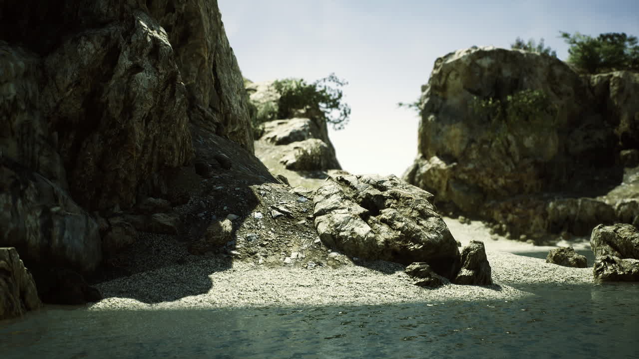 Rocky beach landscape with clear sky and scattered greenery in the distance