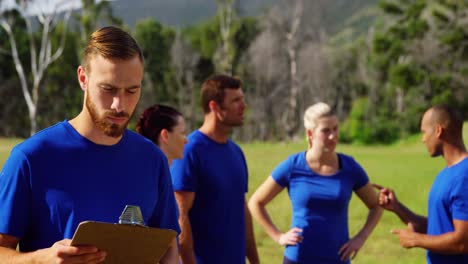 hombre de pie y sosteniendo un clipboard en el campamento de entrenamiento 4k
