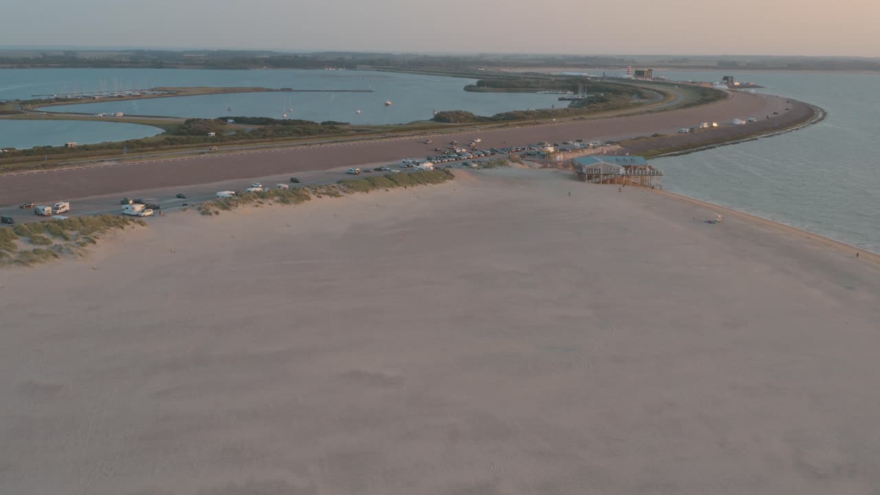 시네마틱 드론 - 네덜란드 북해의 제일란트에서 관광객들과 함께 일몰 시 녹색과 모래가 있는 자연 해변의 공중 파노라마 샷, 30p