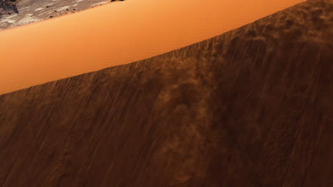 aerial view of wind blowing sand over dunes in the namib desert, sunset in namibia