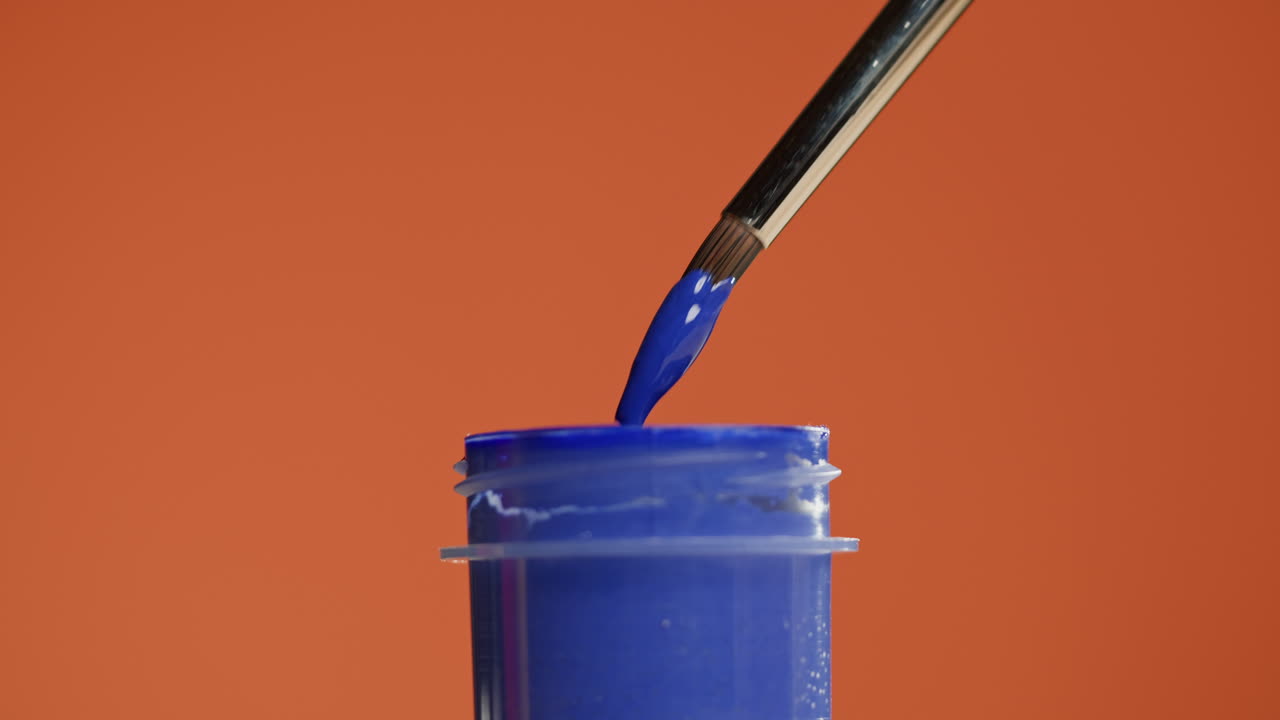 Pinsel taucht in blaue Farbe mit einem tropfenden Tropfen
