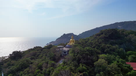 drone tracks past thai gold buddha statue in morning sun