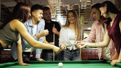 friends play rock paper scissors near a pool table