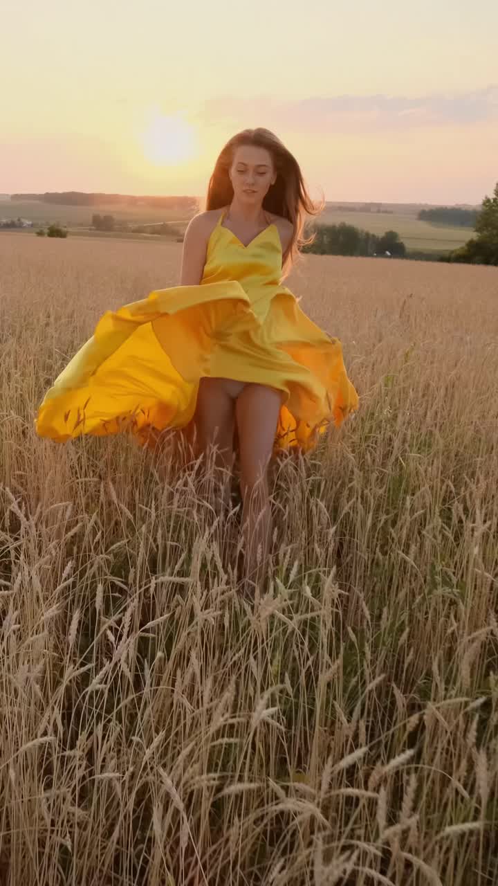 Woman in yellow dress running in a wheat field at sunset