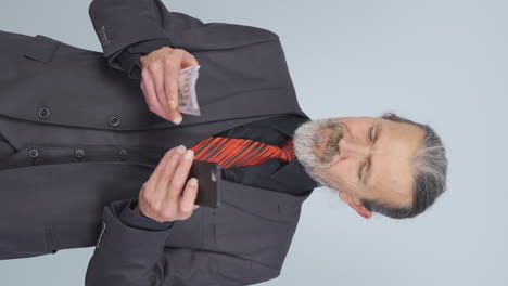 video vertical de un viejo hombre de negocios comprando por teléfono con una tarjeta de crédito.