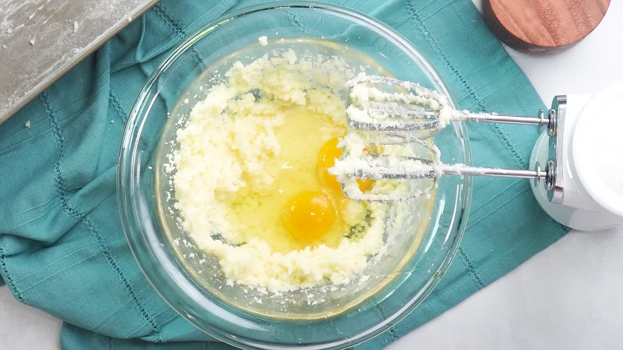Making a dessert called Red Raspberry Tea Cake made with fresh berries and vanilla buttercream frosting. Great for Tea Parties. Cracking room temperature eggs into the cake batter to mix together