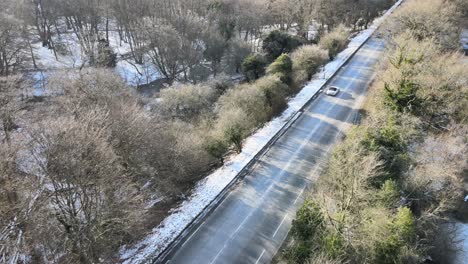 Camino-A-Través-Del-Bosque-En-Invierno,-Reino-Unido,-Imágenes-Aéreas-De-La-Cubierta-De-Nieve-Ligera