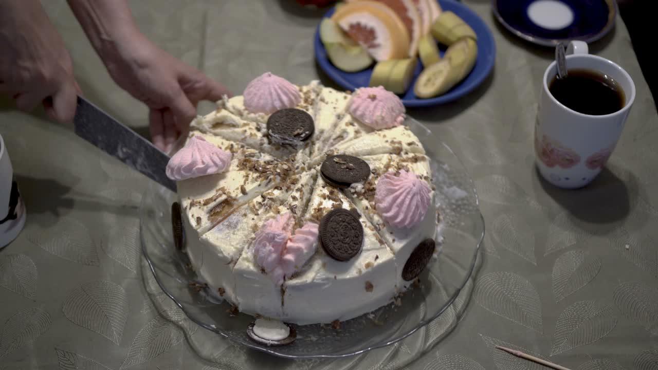 en primer plano, mamá corta y distribuye a los niños pedazos de un hermoso y dulce pastel, que está decorado con malvaviscos, crema y galletas. el concepto de una fiesta familiar para niños. sin rostro. 4k.