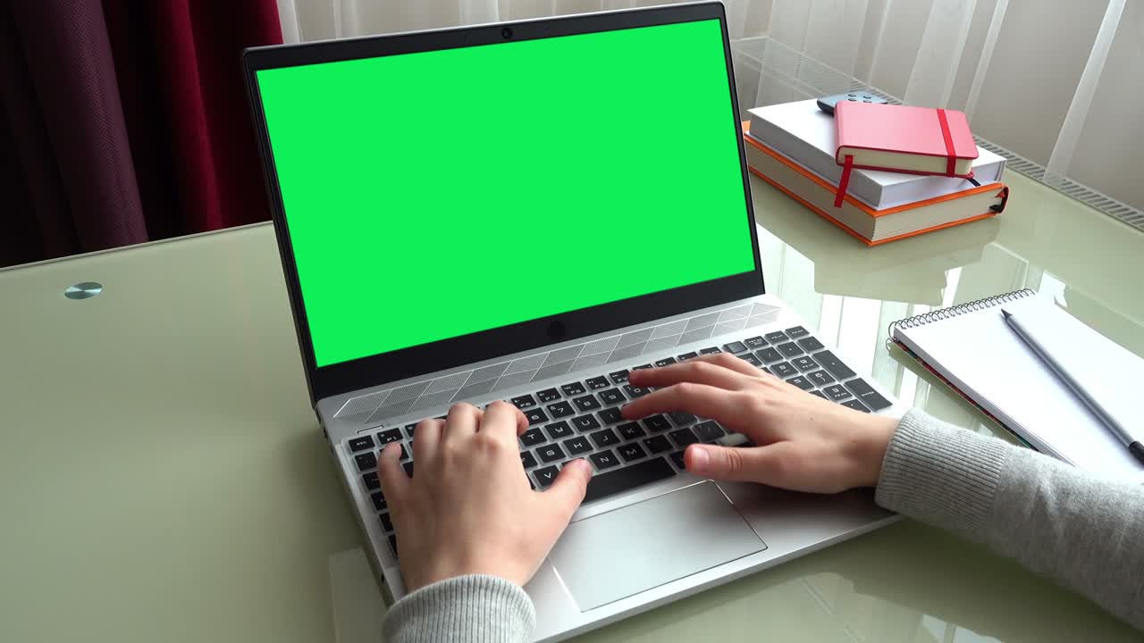 The girl working at home office hands on keyboard. The screen is a green background.