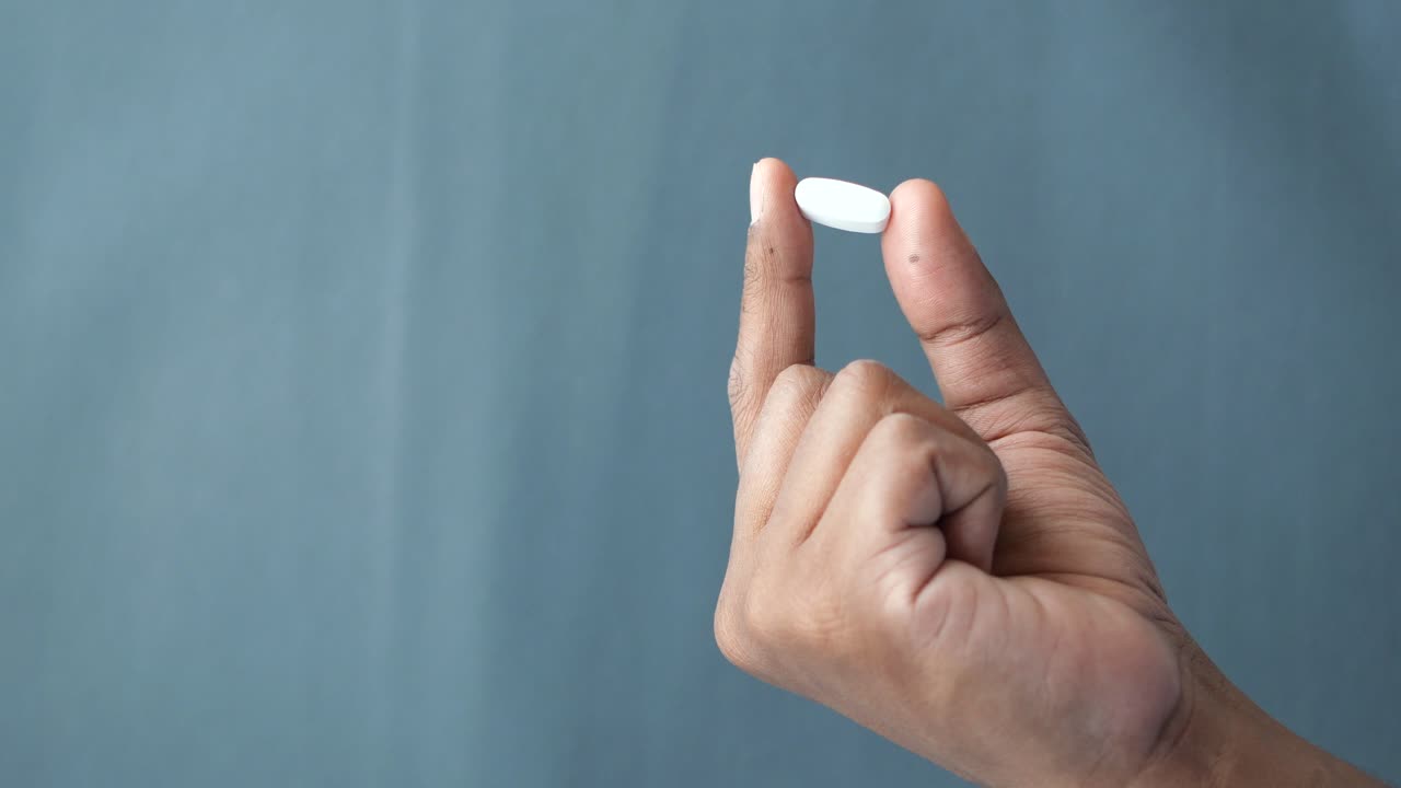 persona que sostiene una píldora blanca