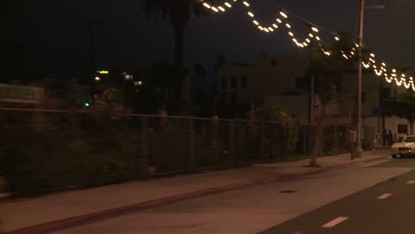 a car travels along a street at night in santa monica california as seen through the rear window at an angle 3