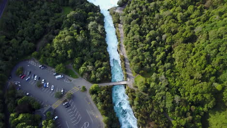 aerial shot of white and blue rapids on river next to a forest tilting up to the horizon