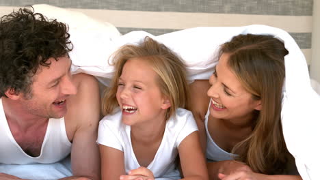 una familia linda escondiéndose en su cama.