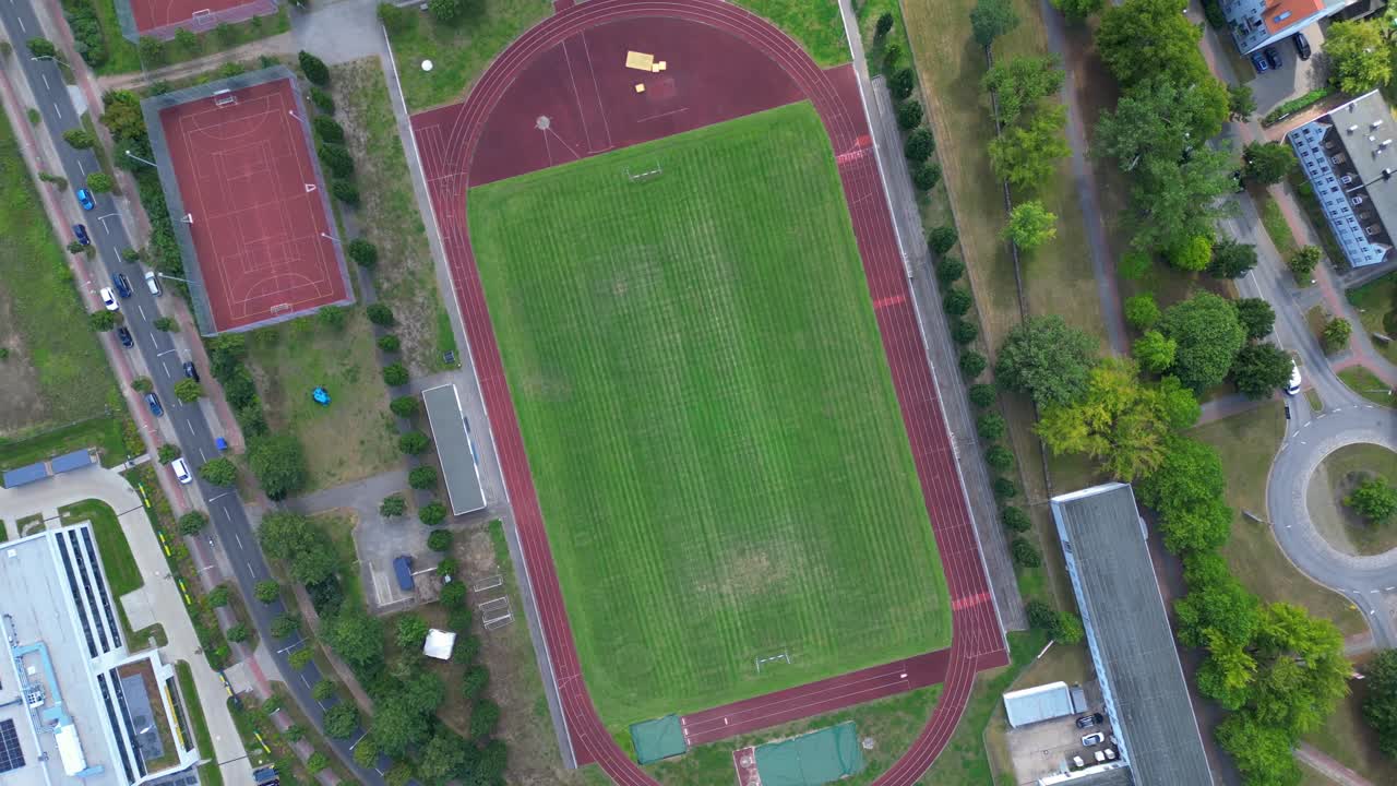 sports facilities at Hennigsdorf high school, including a soccer field, running track and other buildings in residential areas. Unique aerial view vertical bird's eye view rotation to right drone