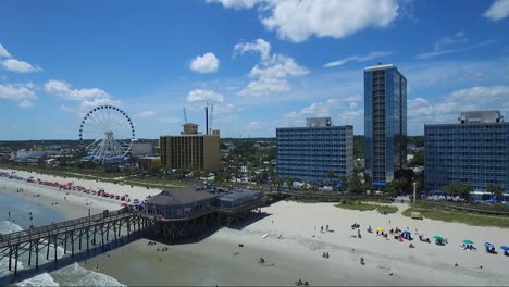 Drone-Volando-Cerca-De-Resorts-Frente-Al-Mar,-Muelle-Y-Rueda-Del-Cielo-En-Myrtle-Beach-Sc