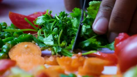 Cutting-fresh-Coriander-on-a-white-surface-with-lots-of-different-vegetables-in-the-foreground