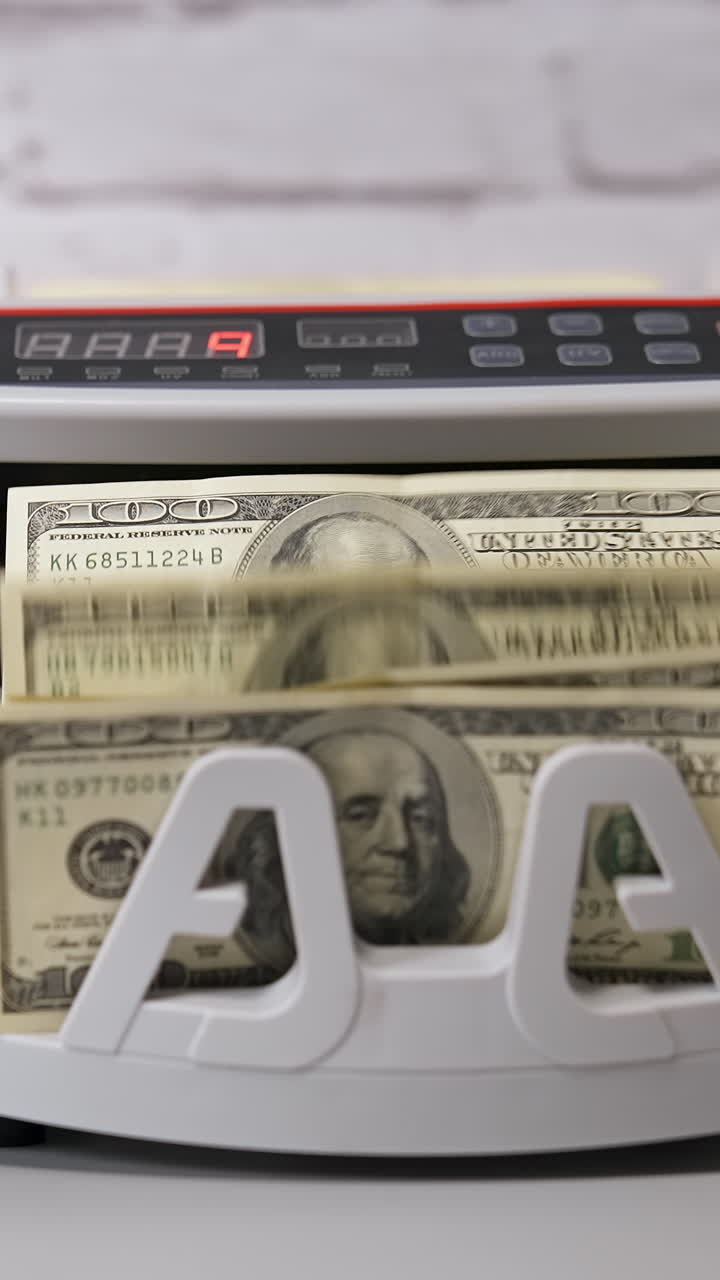 Electronic cash counting machine. Bank financial operations and calculating dollar banknotes. Female hand puts paper money into automatic equipment for counting bills. Vertical video