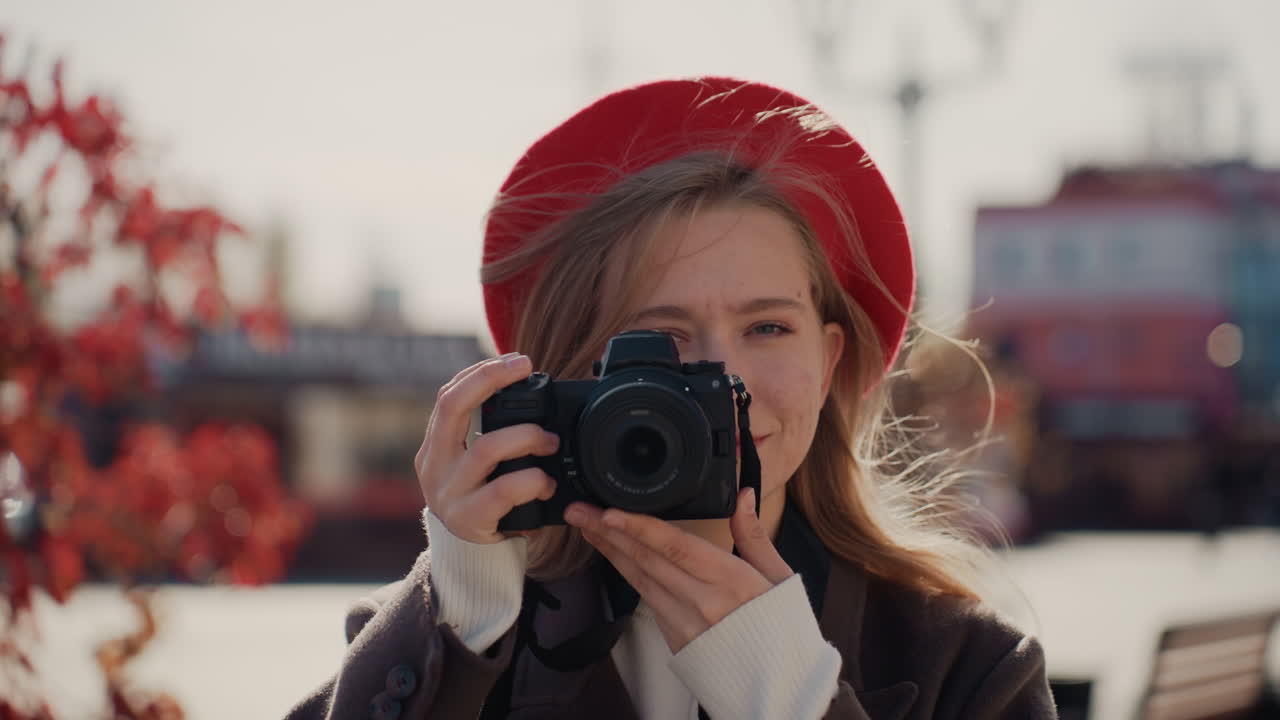Giovane donna che tiene la macchina fotografica vicina, porta l'obiettivo all'occhio e cattura ritratti spontanei con sfondo bokeh, azione dell'otturatore, messa a fuoco creativa, in una scena urbana autunnale e con l'energia di una fotografa amatoriale.