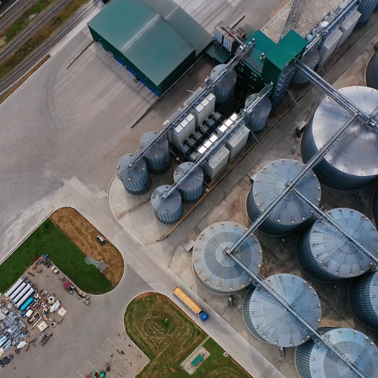 Silo steel tanks standing in rows at the modern plant. Aerial view of the hangars, railways and truck at the agricultural enterprise