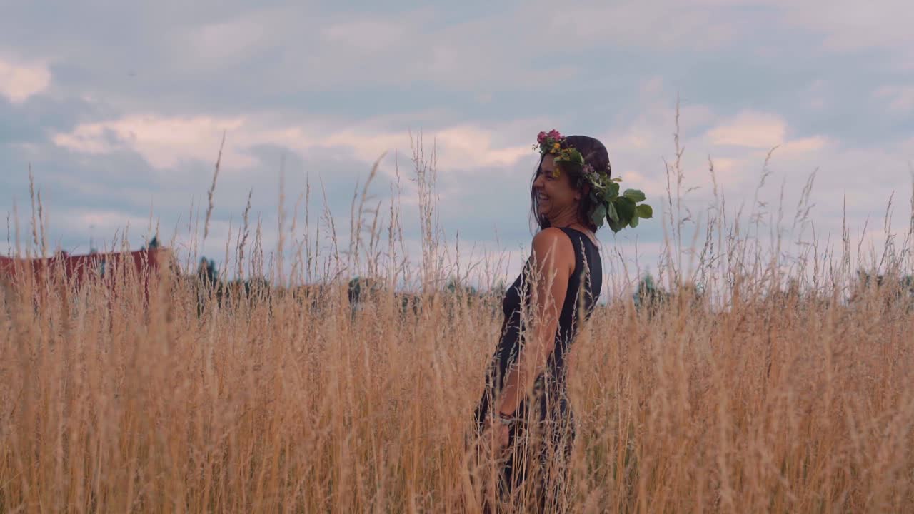Stunning girl with a flower crown standing in a cornfield. With beautiful looking clouds. Big smile