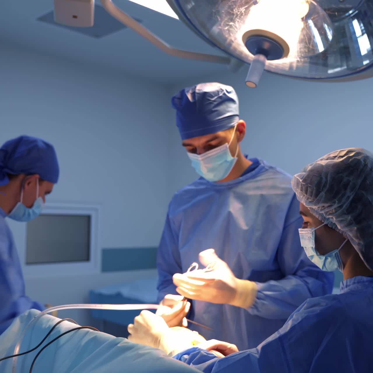 Operating doctor uses metal instruments. Male assistant prepares tools for the surgeon and passes them to a doctor