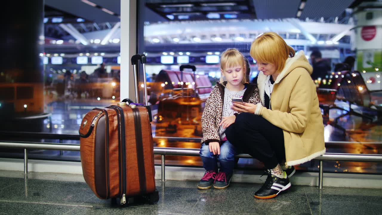 mamá e hija contra la ventana del aeropuerto