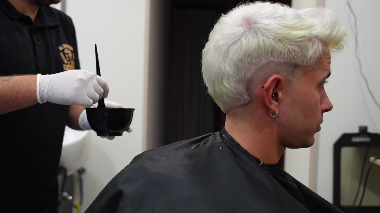 Medium shot of client nodding as hairdresser explains bleaching while mixing product in a small bowl