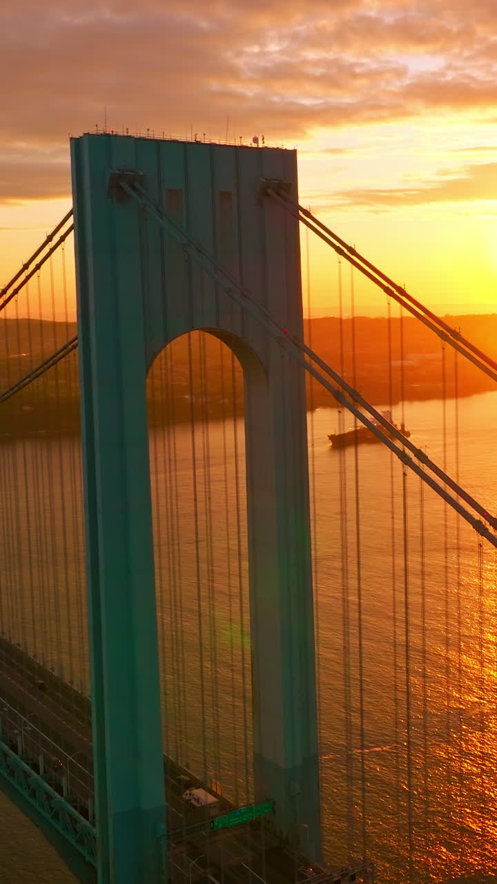 Bright huge sun reflecting in the East River. Beautiful Bronx-Whitestone bridge against sun setting over the city. Vertical video
