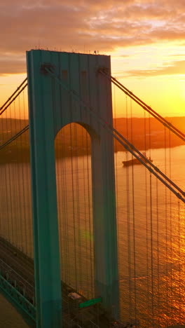 bright huge sun reflecting in the east river. beautiful bronx-whitestone bridge against sun setting over the city. vertical video