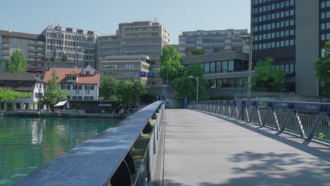Panning-Shot-of-Pedestrian-Bridge-over-Canal-in-Zurich,-Switzerland,-Midday