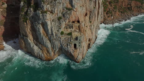 porto flavia: fantástica foto aérea del antiguo puerto minero de la isla de cerdeña y las olas que golpean el acantilado