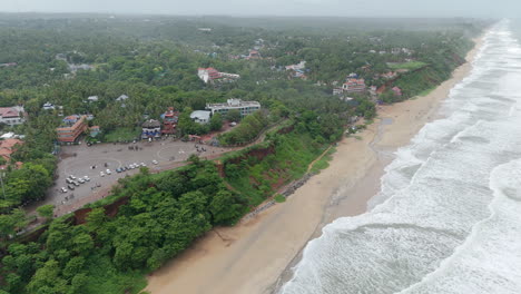 Shoreline-of-Varkala-Cliff-Beach,-drone-view-of-Varkala-beach-from-the-top-of-the-cliff-also-known-as-Papanasham-Beach,-Thiruvananthapuram,-Kerala,-India