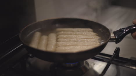 Man-or-woman-prepare-sausages-in-a-pan
