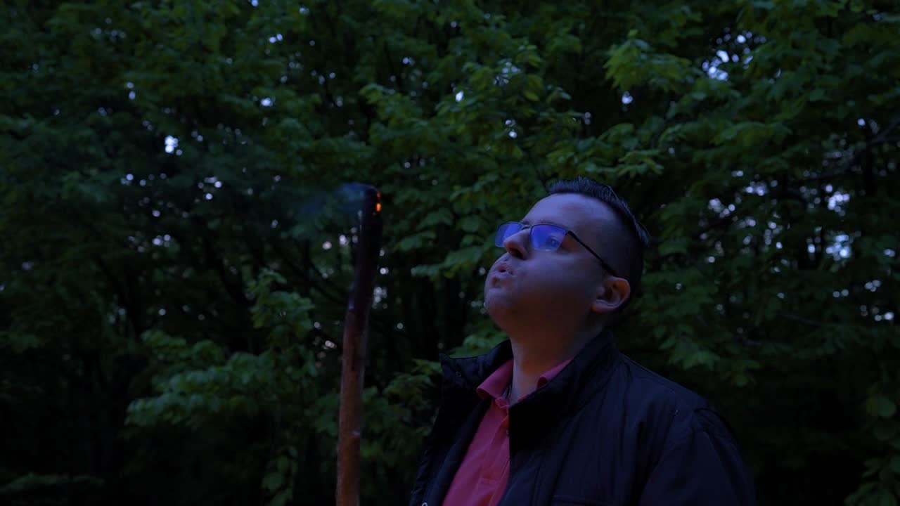 A lone camper blowing the embers of a burning wood at a campsite located at Strandzha Mountain in Bulgaria.