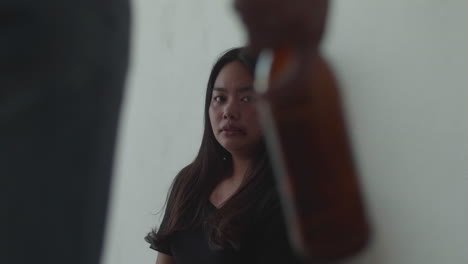 woman scared of a man holding a bottle
