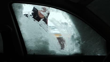 la ventana del coche que cubre la nieve está siendo limpiada por una mujer en invierno