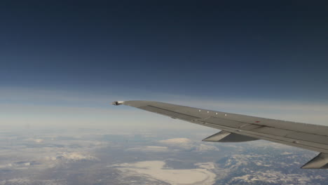 aerial view of snow capped mountains out of from flying airplane window shot in 4k high resolution